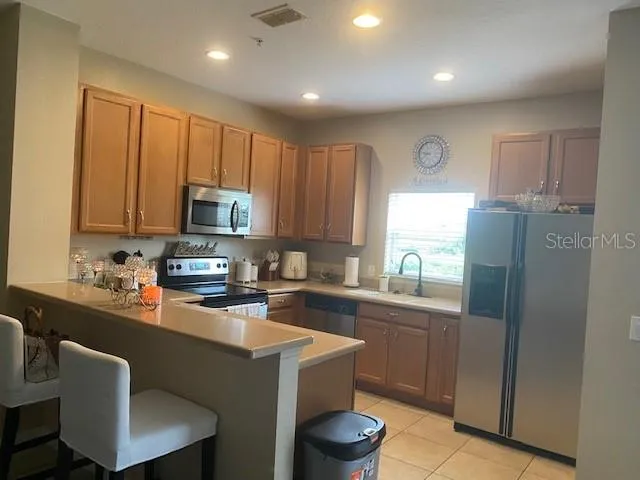 a kitchen with stainless steel appliances a sink a stove a refrigerator cabinets and a window