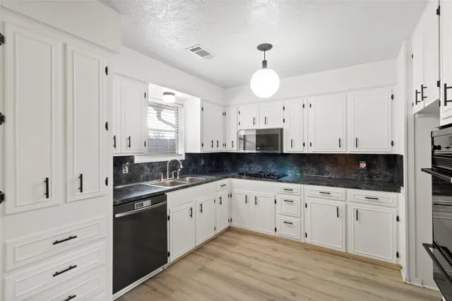 a kitchen with granite countertop white cabinets white stainless steel appliances and sink