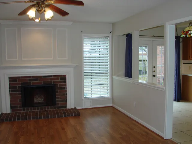 a view of an empty room with wooden floor fireplace and a window