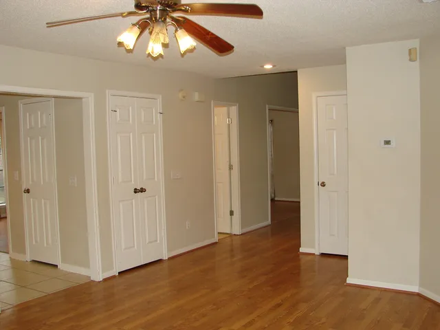 a view of empty room with wooden floor and fan