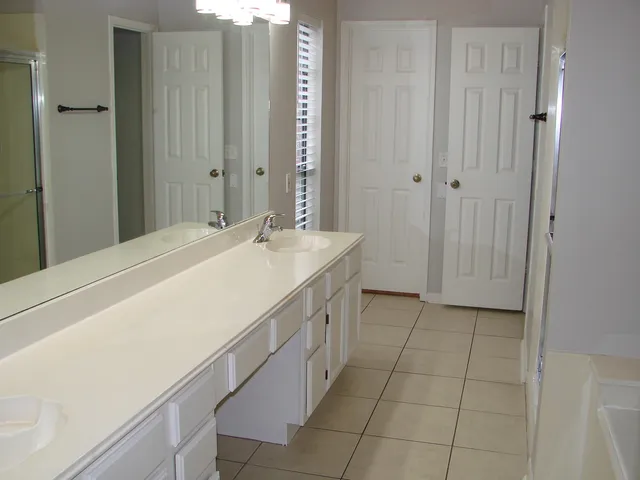 a spacious bathroom with a granite countertop sink a mirror and a bathtub