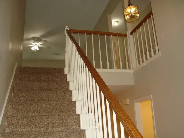 a view of staircase with railing and a chandelier
