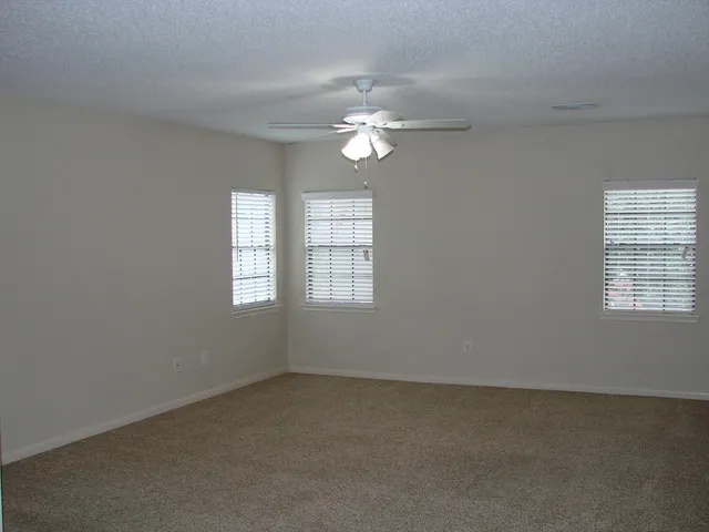 an empty room with a window and a ceiling fan