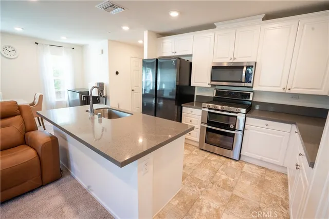 a kitchen with stainless steel appliances granite countertop a sink a stove and refrigerator