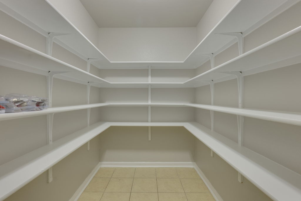210 Cushman Drive Kyle, TX 78640 - Photo 12 of 21 Walk-in pantry featuring extensive shelving, light-colored walls, white trim, and neutral-toned tile flooring