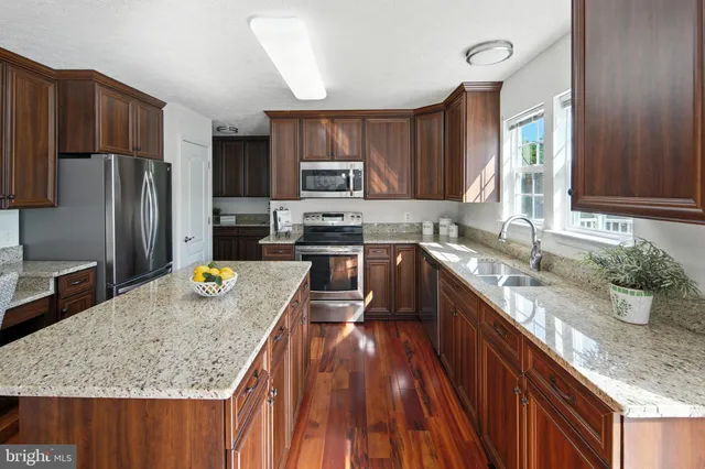 a kitchen with kitchen island granite countertop a sink a counter top space appliances and cabinets