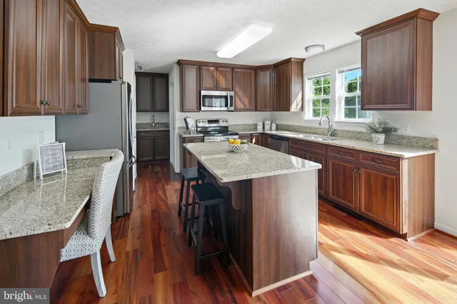 a kitchen with stainless steel appliances granite countertop a table chairs sink refrigerator and cabinets
