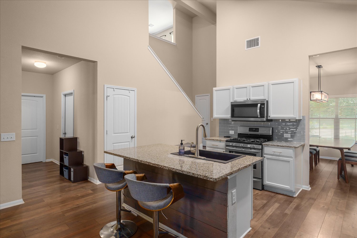 717 Kaluga Trail Leander, TX 78641 - Photo 10 of 40 a kitchen with granite countertop a stove top oven a sink dishwasher a dining table and chairs with wooden floor