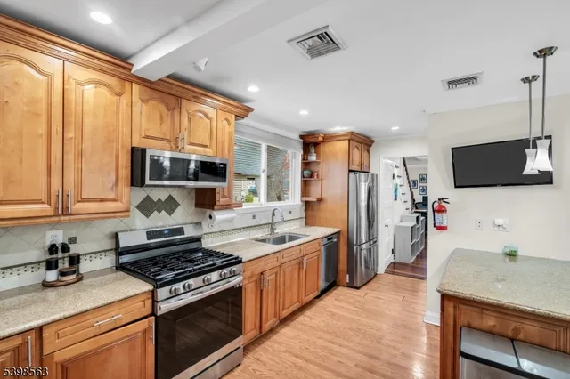 a kitchen with stainless steel appliances granite countertop a stove top oven a sink dishwasher a refrigerator and cabinets with wooden floor