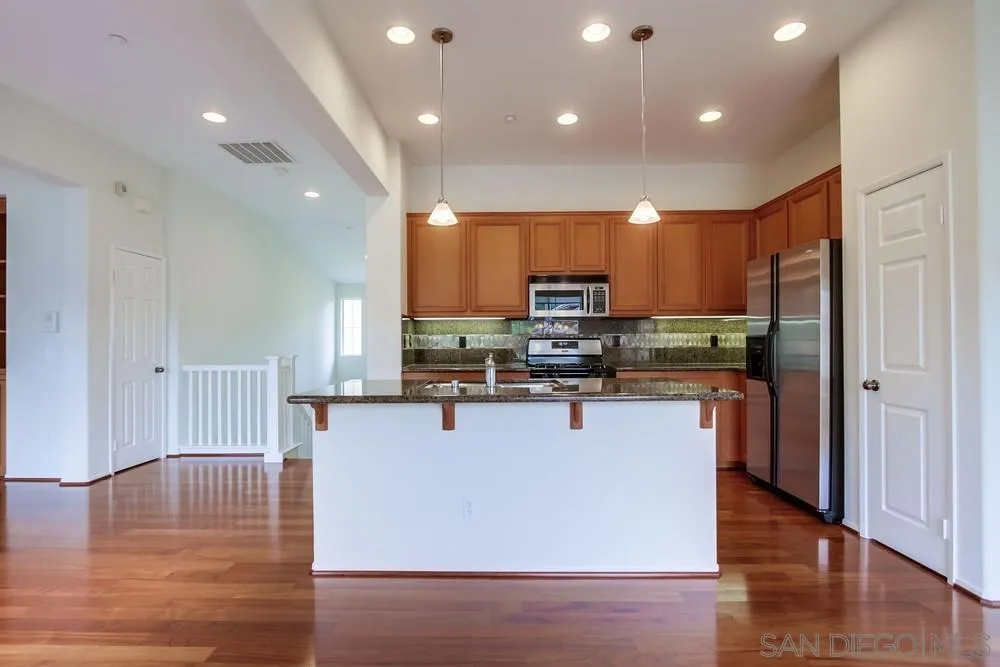 1631 Avery Road San Marcos, CA 92078 - Photo 14 of 32 a kitchen with stainless steel appliances wooden floors wooden cabinets and sink