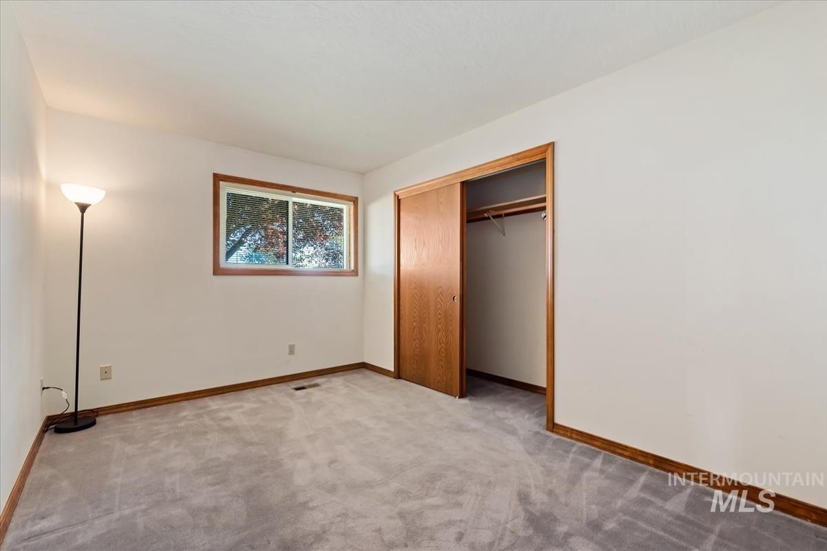 8275 Washoe Road Fruitland, ID 83619 - Photo 22 of 43 Light gray carpeting, white walls, wood-trimmed window, and closet with wood sliding doors