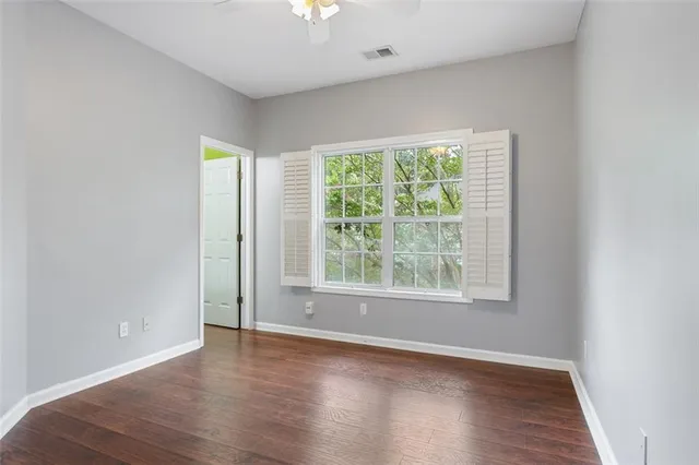 an empty room with wooden floor and windows
