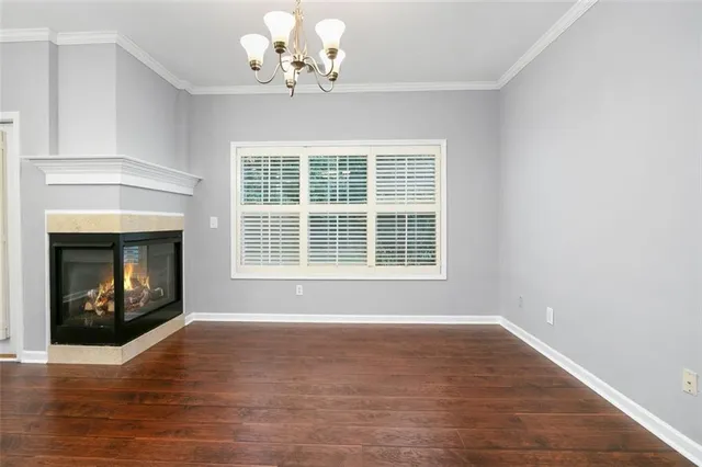 a view of an empty room with wooden floor fireplace and a window