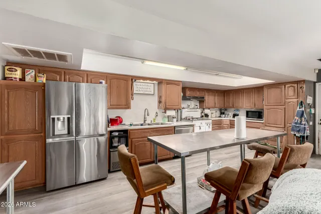a kitchen with stainless steel appliances a refrigerator a stove a dining table and chairs