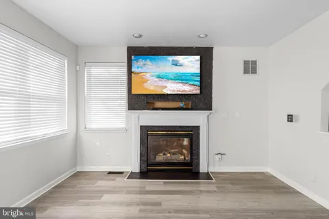 a living room with a fireplace a flat screen tv and a window