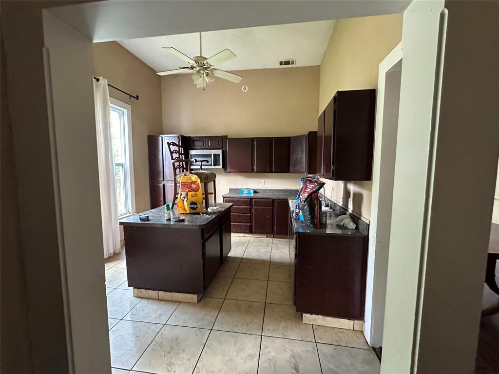 1405 Caddo Street Commerce, TX 75428 - Photo 3 of 8 a kitchen with a refrigerator and a sink