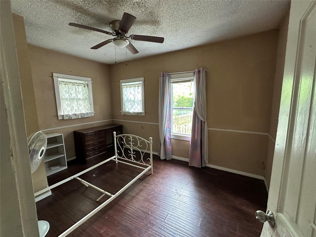 1405 Caddo Street Commerce, TX 75428 - Photo 7 of 8 a livingroom with wooden floor and a ceiling fan