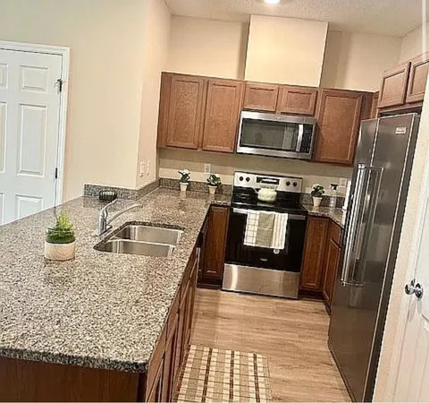 a kitchen with stainless steel appliances granite countertop a sink stove and refrigerator
