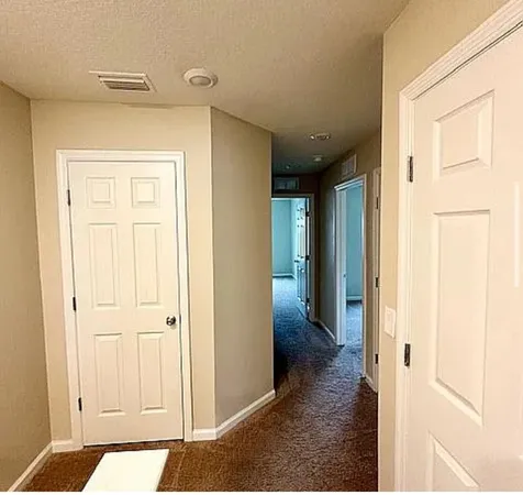 a view of a hallway with closet and a bathroom