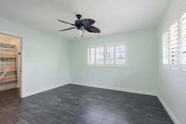 an empty room with windows and fan