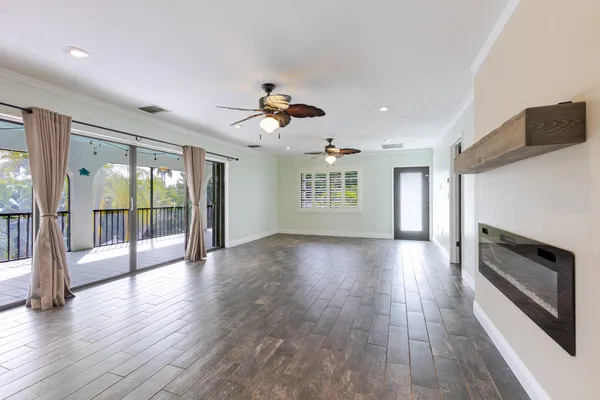 a view of an empty room with a window and wooden floor