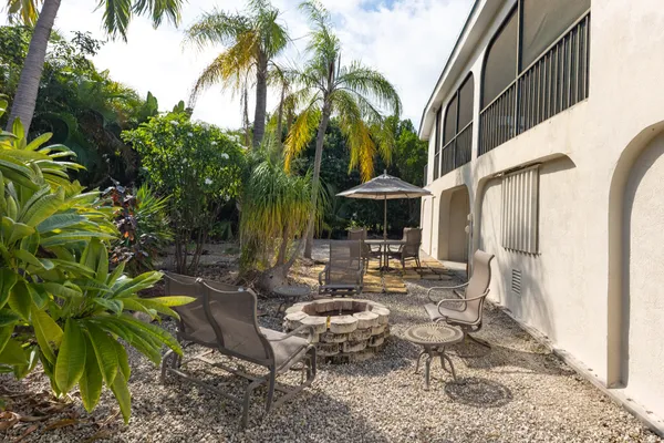 a view of a patio with table and chairs potted plants and palm tree