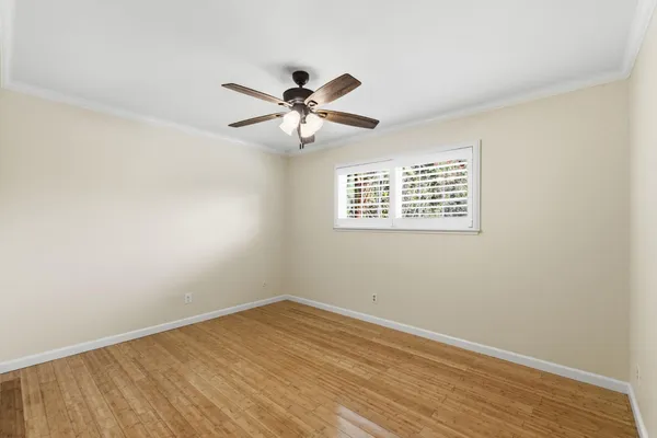 a view of empty room with wooden floor and fan