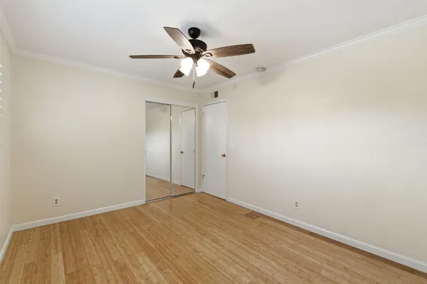 a view of a big room with wooden floor closet and ceiling fan