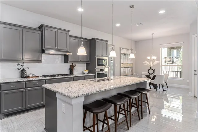 a kitchen with stainless steel appliances kitchen island granite countertop a stove refrigerator and cabinets