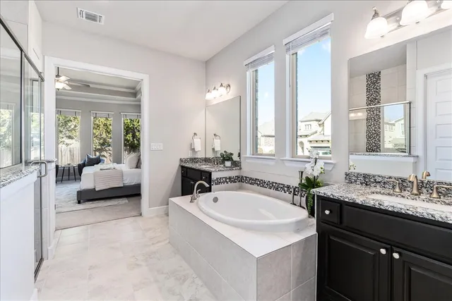a bedroom with a large bed a chandelier and windows