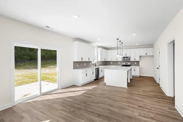 a large white kitchen with a sink a counter top space and stainless steel appliances