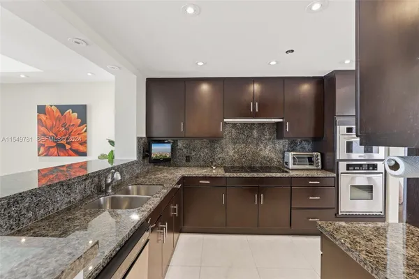 a kitchen with stainless steel appliances granite countertop a refrigerator a sink a stove and oven