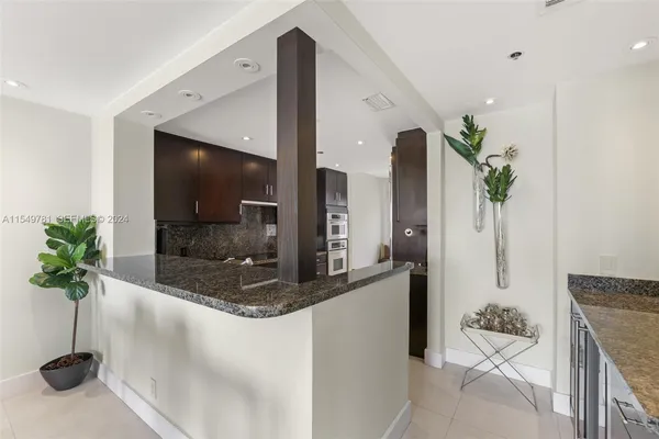 a kitchen with stainless steel appliances kitchen island granite countertop a refrigerator and a sink