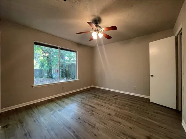 a view of an empty room with wooden floor and a window