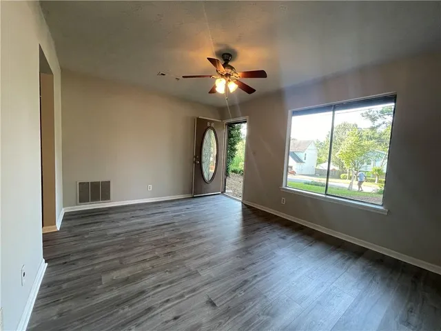 a view of an empty room with window and wooden floor
