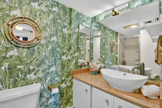 a bathroom with a granite countertop bathtub sink vanity mirror and toilet