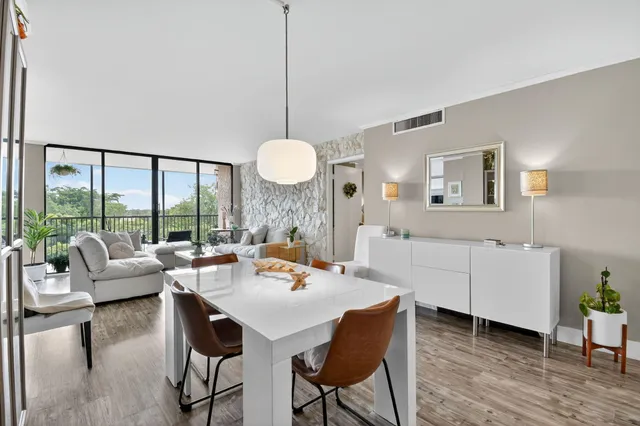 a living room with furniture floor to ceiling window wooden floor and a flat screen tv