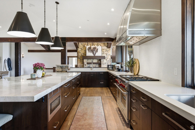 7885 North Rabbitbrush Court, Unit 13 Park City, UT 84098 - Photo 15 of 88 Gourmet kitchen featuring a large central island, professional-grade range, stainless steel range hood, dark wood cabinetry, and light-toned countertops