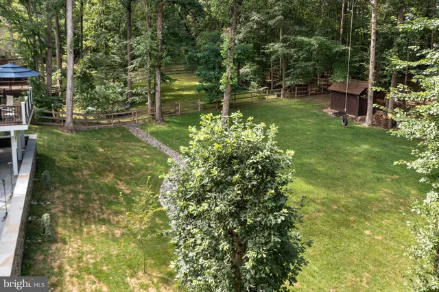 an aerial view of a residential houses with outdoor space and trees