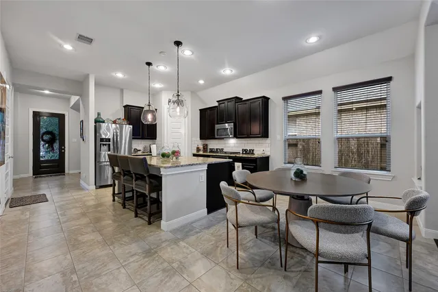 a kitchen with a dining table chairs and refrigerator