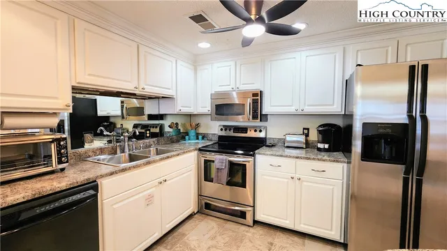 a kitchen with a sink stainless steel appliances and white cabinets