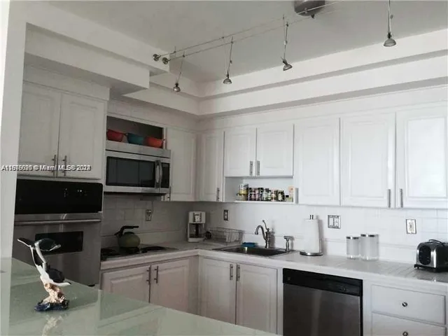 a kitchen with stainless steel appliances a sink a stove a microwave a refrigerator and cabinets