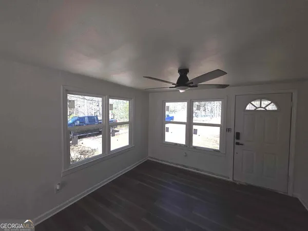 an empty room with wooden floor chandelier and windows