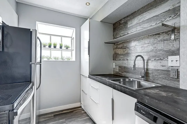 a kitchen with granite countertop a sink stainless steel appliances and cabinets
