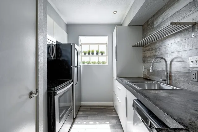 a kitchen with granite countertop a sink and stainless steel appliances