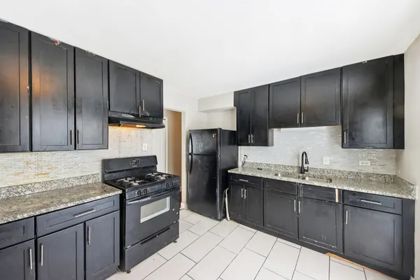 a kitchen with granite countertop stainless steel appliances a stove sink and cabinets