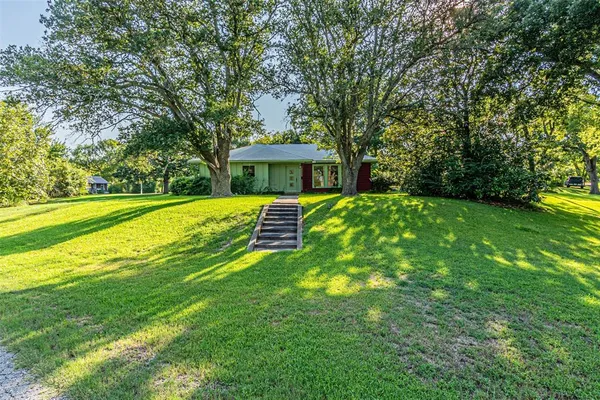 a view of a house with a big yard and large trees