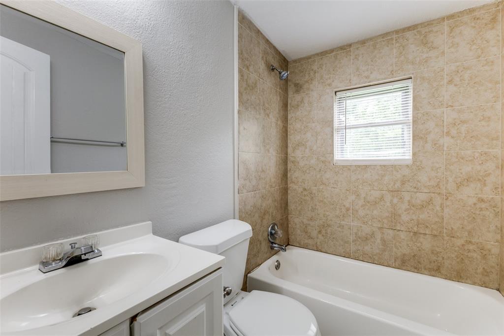 12129 Spring Branch Drive Balch Springs, TX 75180 - Photo 10 of 11 Full bathroom with a textured wall, vanity, and bathtub / shower combination
