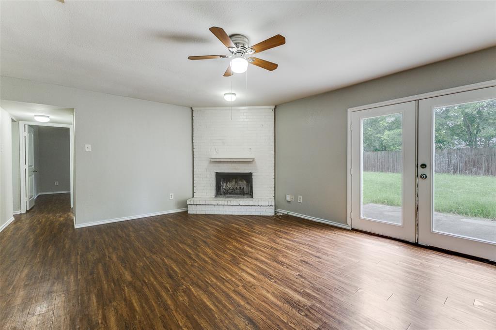 12129 Spring Branch Drive Balch Springs, TX 75180 - Photo 2 of 11 Unfurnished living room with dark wood-type flooring, a ceiling fan, a fireplace, and french doors