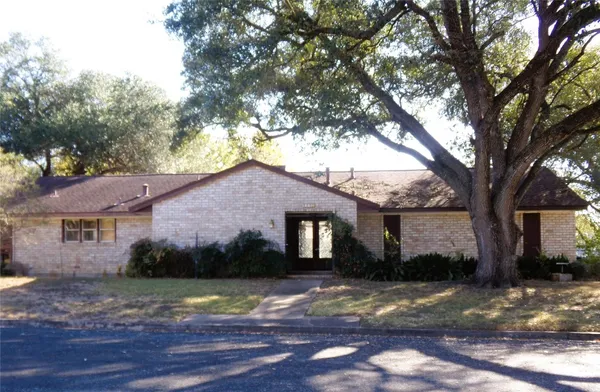 a view of a yard in front of a house with large tree